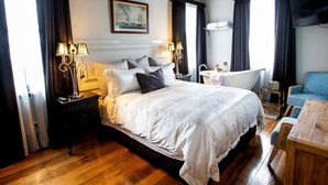 Una habitación de hotel con una cama grande, lámparas de noche, un televisor, un escritorio y una silla.