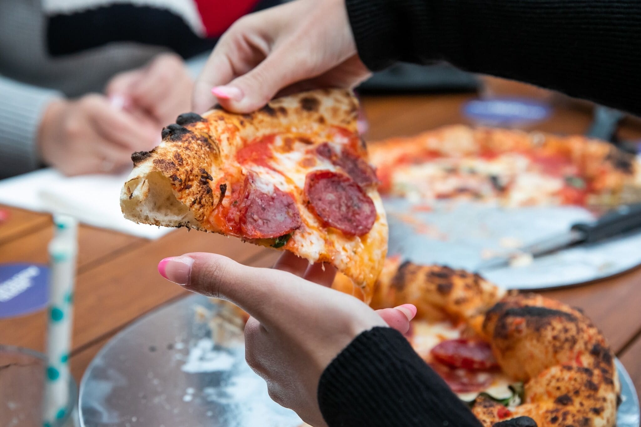 A person holding a slice of pizza with pepperoni and cheese.
