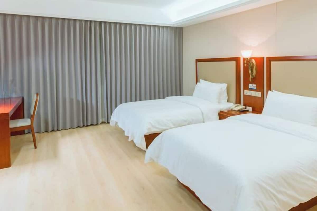 Hotellihuone, jossa on kaksi sänkyä, työpöytä ja tuoli.