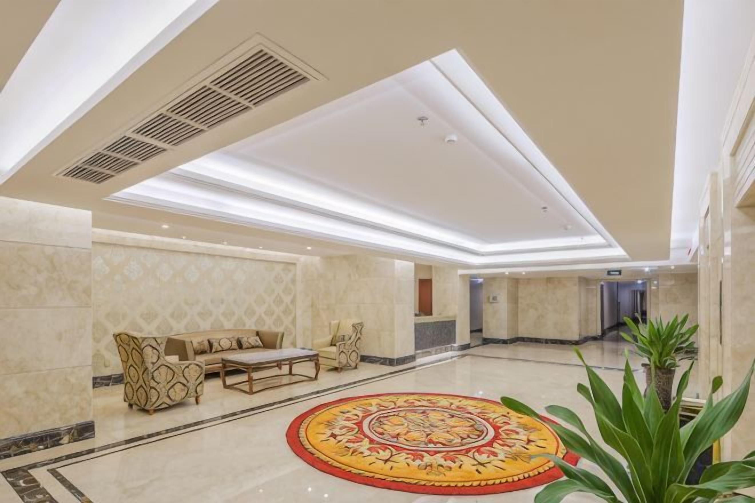 A spacious lobby with a patterned carpet, seating area, and a reception desk.