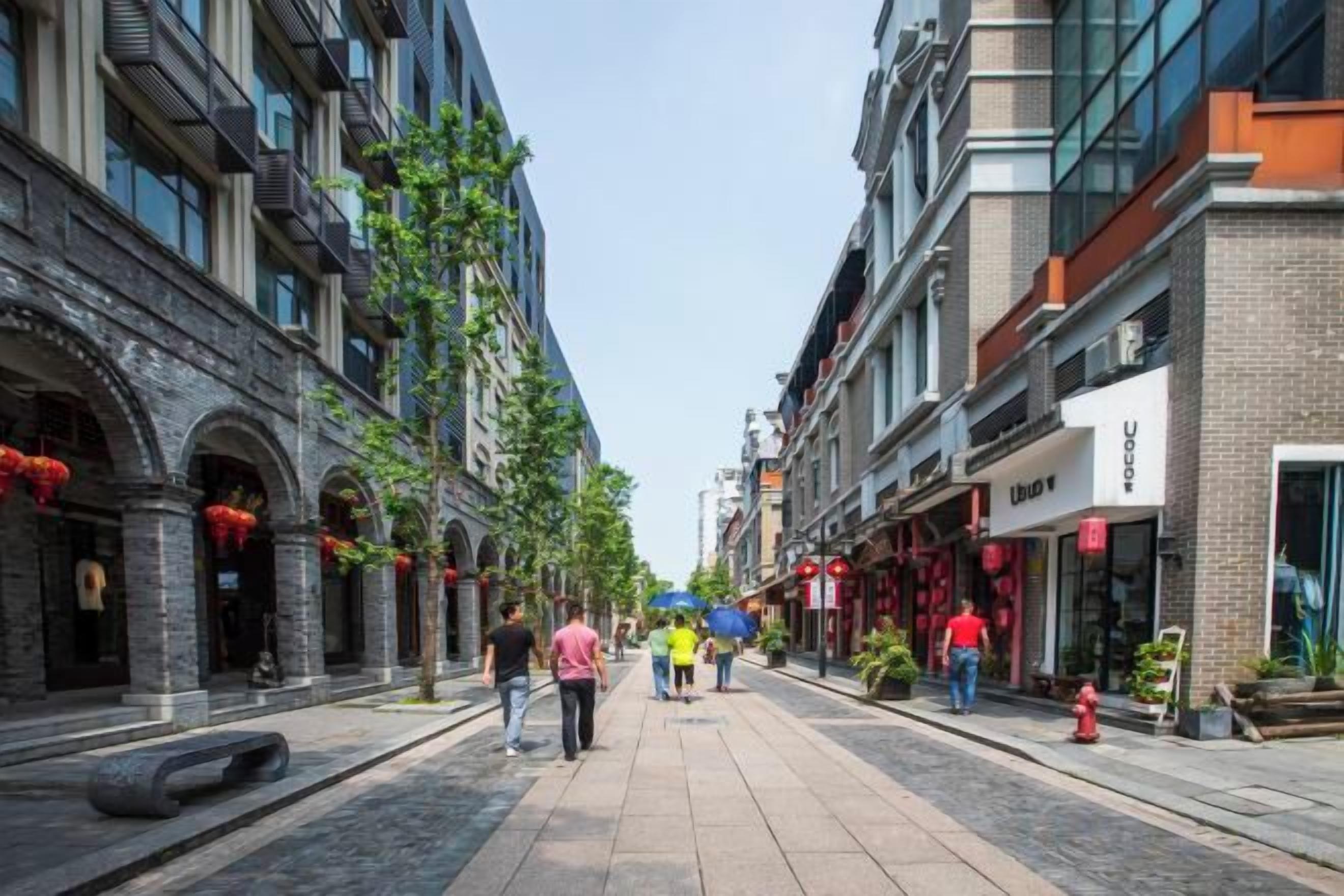 A pedestrian street lined with buildings, some with storefronts and others with residential units.