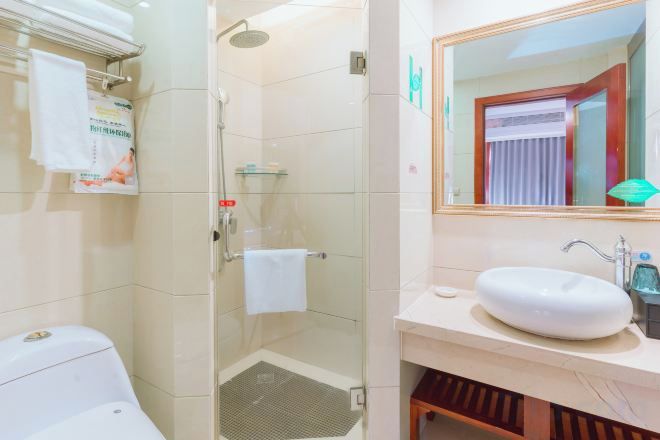 A bathroom with a glass-enclosed shower, a white sink, and a mirror above it.