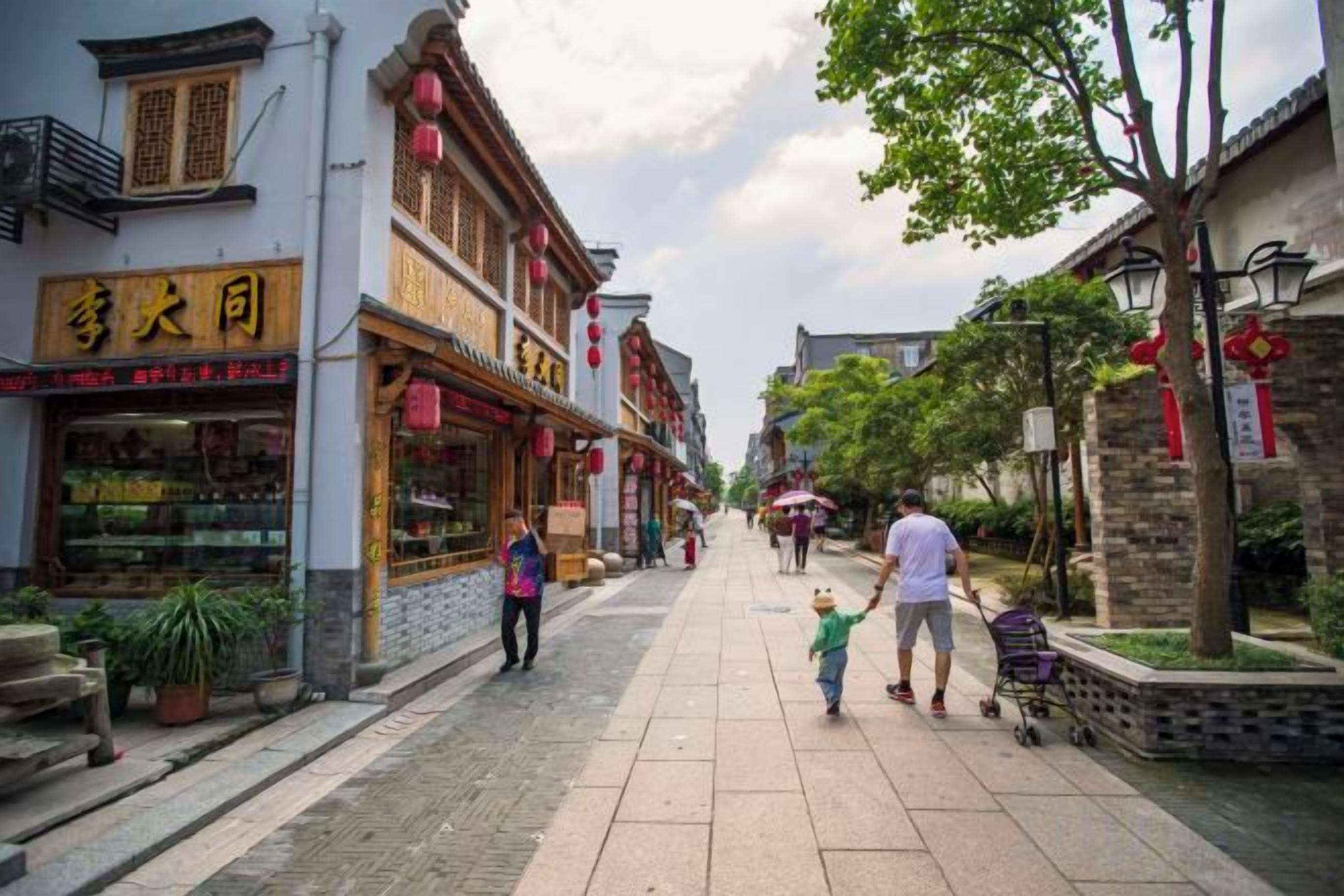 A pedestrian street with traditional architecture, shops, and a clear sky.