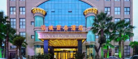 L’entrée d’un hôtel, avec une grande façade arquée en verre et une enseigne en chinois et en anglais.