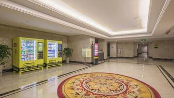 Un vestíbulo de hotel con máquinas expendedoras, una alfombra estampada y un suelo pulido.
