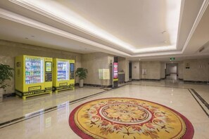 Um saguão de hotel com máquinas de venda automática, carpete estampado e piso lustroso.