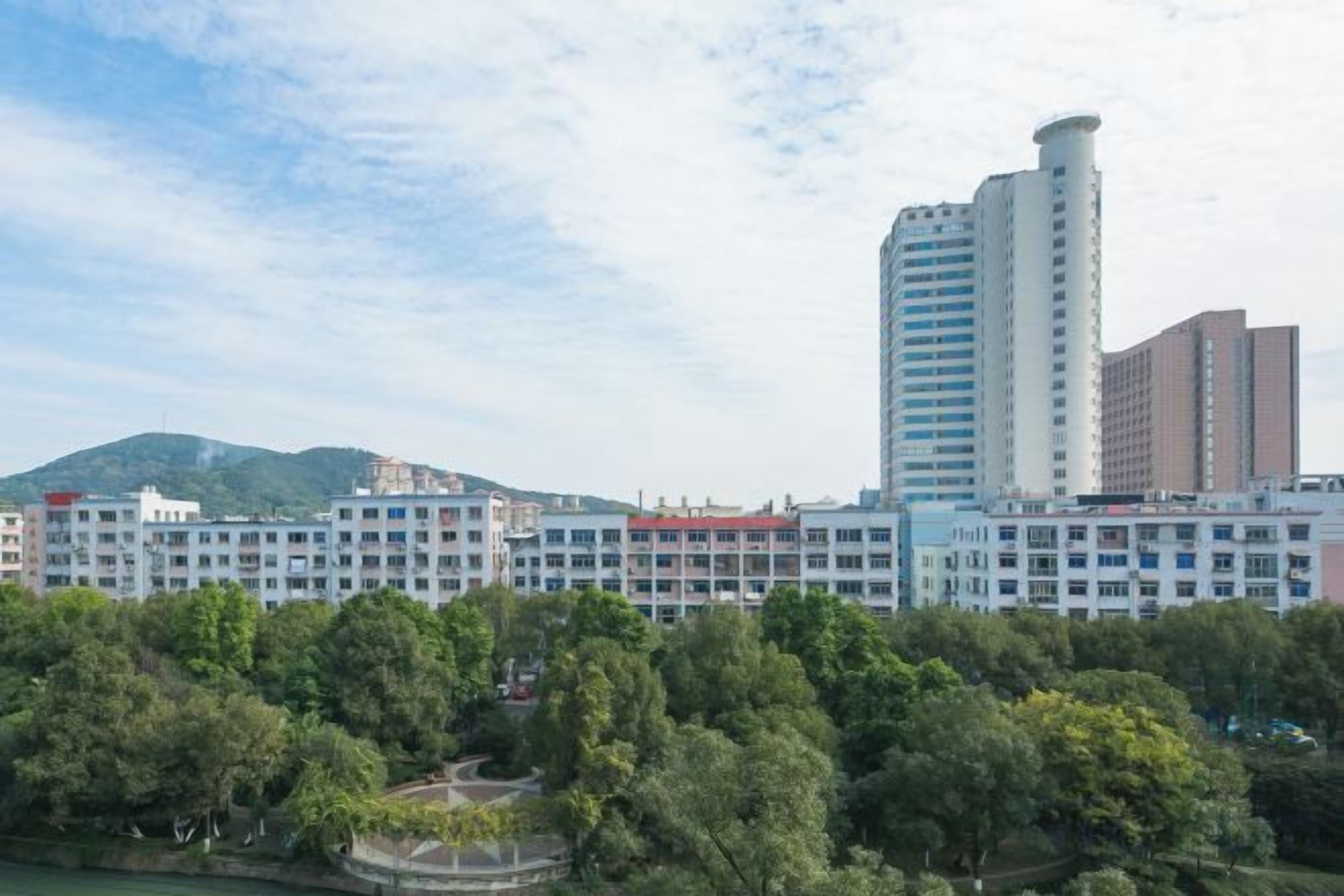 A multi-story hotel with a modern design, surrounded by greenery and a body of water.