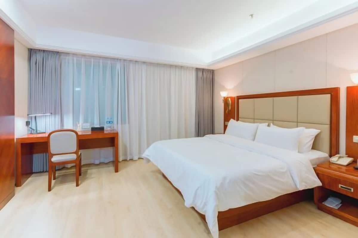 Hotellihuone, jossa on suuri sänky, työpöytä ja tuoli.