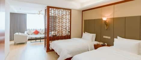 Una habitación de hotel con dos camas, un sofá, un separador decorativo y una lámpara de pared.