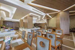 A modern hotel dining area with wooden furniture, a central island, and a contemporary ceiling design. - Yin Cheng Business Hotel (Rui'an)
