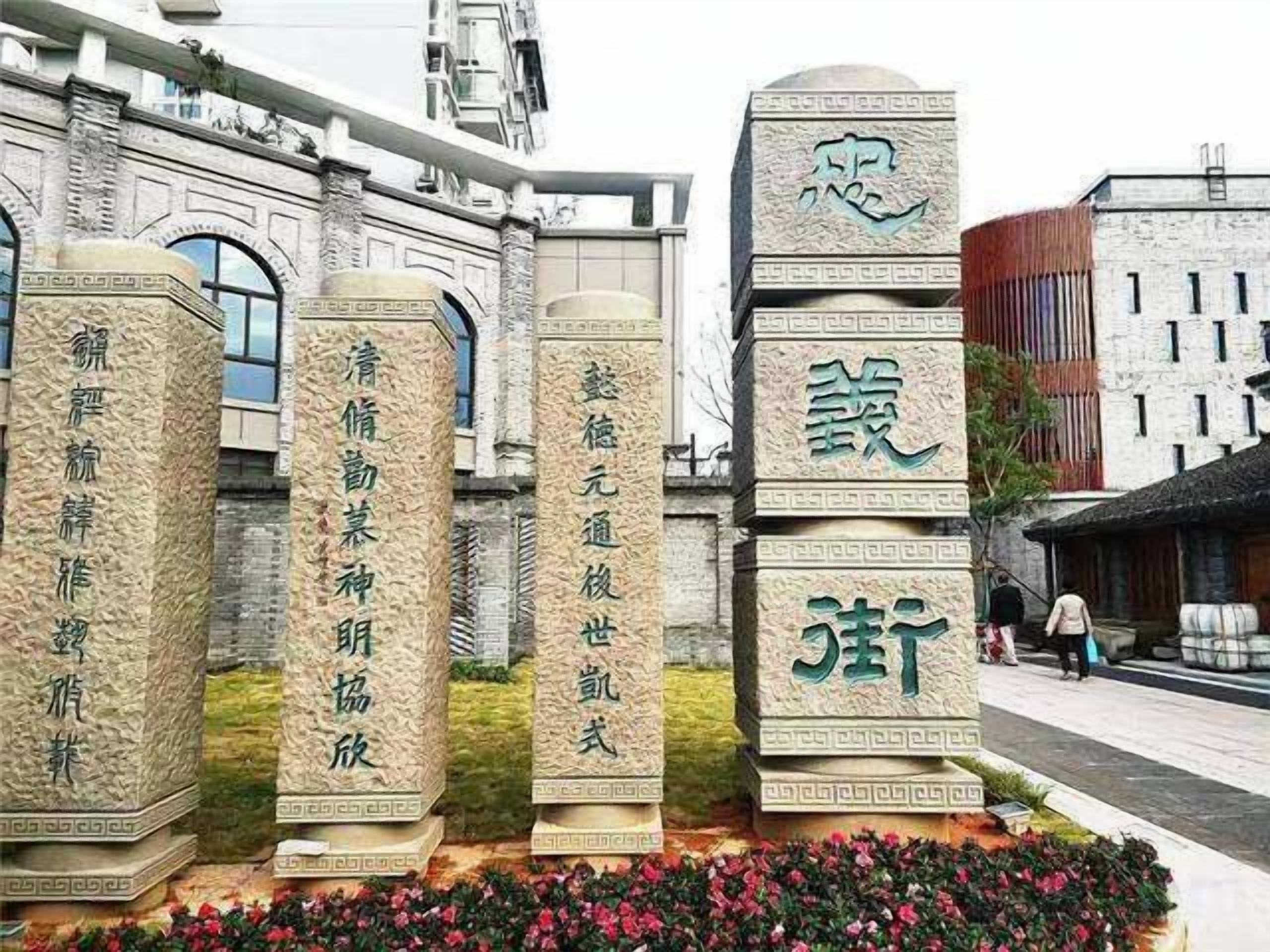 Una hilera de monumentos de piedra con inscripciones, frente a una fachada de edificio de arquitectura clásica.