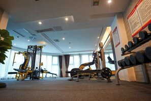 A gym with weightlifting equipment, a squat rack, and a rack of dumbbells. - Jun'an International Hotel (Cenxi)