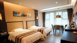 A hotel room with two beds, a desk, and a dining area. - Jun'an International Hotel (Cenxi)