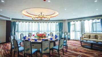 A conference room with a round table, chairs, a sofa, and a chandelier.