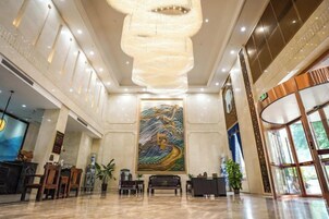 Un vestíbulo amplio con un gran mural, una mesa de recepción y una araña.