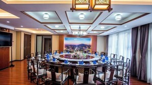 A conference room with a round table, chairs, and a large painting on the wall. - Jun'an International Hotel (Cenxi)