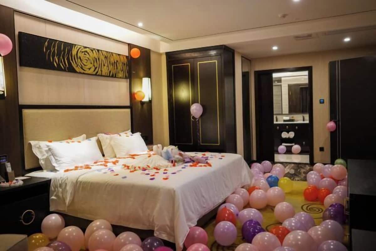 A hotel room with a large bed, a wardrobe, and a mirror.