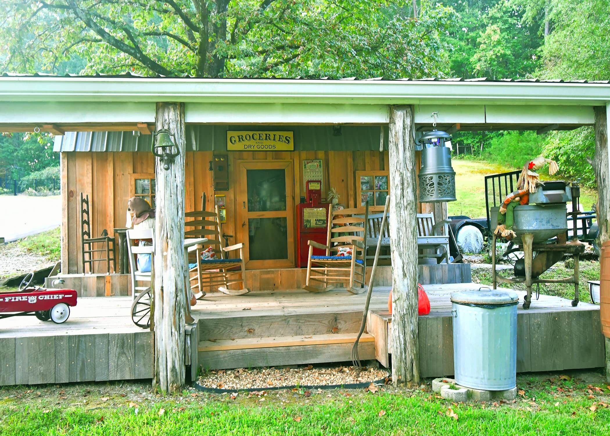 A rustic wooden building with a porch, a sign reading "Groceries and Dry Goods," and a vintage fire truck outside.