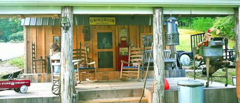 A rustic wooden building with a porch, a sign reading "Groceries and Dry Goods," and a vintage fire truck outside.