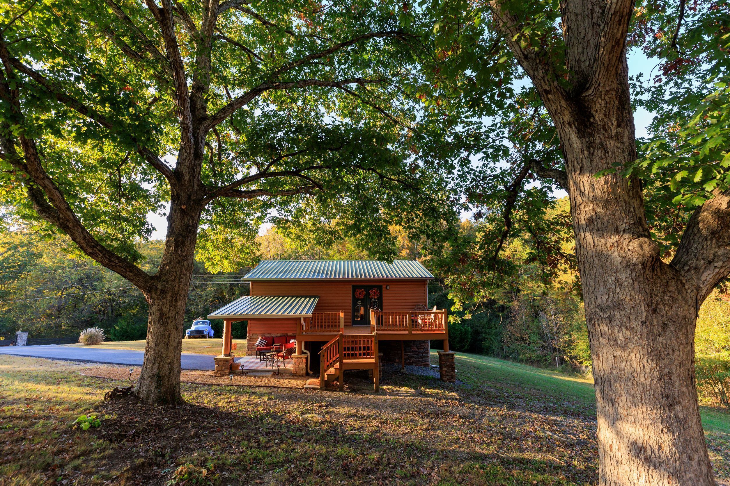 Eine Hütte mit Veranda, umgeben von Bäumen.