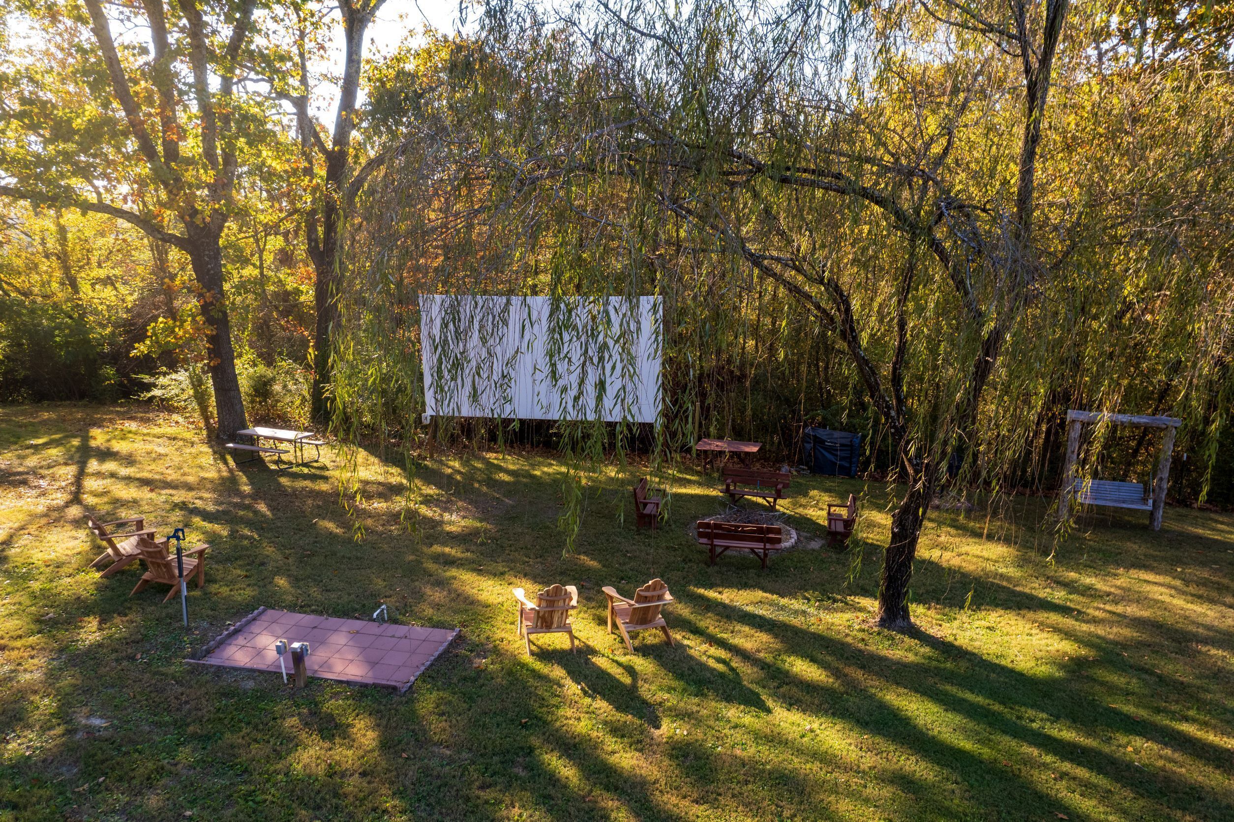 Un espacio al aire libre con mesas de picnic y sillas, rodeado de árboles.