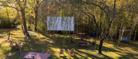 Un espacio al aire libre con mesas de picnic y sillas, rodeado de árboles.