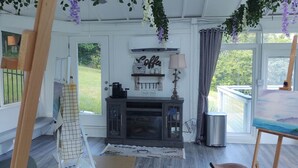 A cozy room with a fireplace, a coffee-themed decor, and a view of the outdoors. - The Ole Pole Barn at Dry Creek Hideaways (Middle Valley)