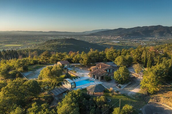 A villa with a swimming pool, solar panels, and a view of the surrounding landscape. - Il Romitoio 12 (Castiglion Fiorentino)