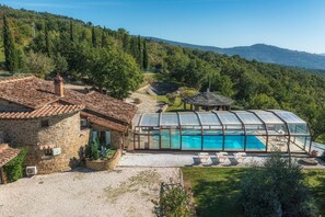 A house with a swimming pool, stone walls, and a view of the surrounding forest. - Il Romitoio 12 (Castiglion Fiorentino)