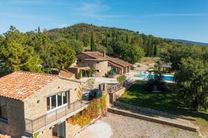 A stone villa with a swimming pool, surrounded by lush greenery and hills. - Il Romitoio 12 (Castiglion Fiorentino)