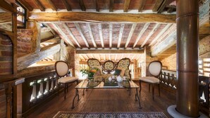 A rustic room with exposed wooden beams, a large column, and a traditional sofa set. - Il Romitoio 12 (Castiglion Fiorentino)