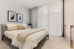 A modern bedroom with a large bed, a nightstand, a lamp, and two framed artworks on the wall. - Terrace Boutique in the Heart of The Rocks (The Rocks)