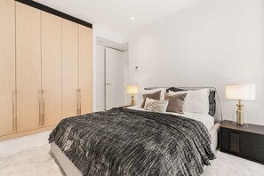 Une chambre à coucher avec un lit, des lampes de chevet, une armoire et une porte.