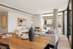A modern living room with a wooden dining table, a grey sofa, and a large window. - Terrace Boutique in the Heart of The Rocks (The Rocks)