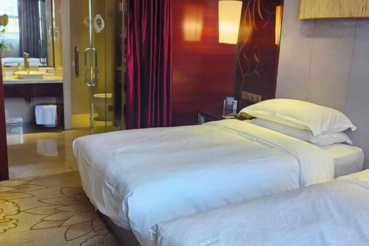 Ein Hotelzimmer mit Bett, Badezimmer mit Glasdusche und Spiegel.