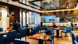 Un ristorante con sedie imbottite blu, pavimento in legno e un moderno design del soffitto.