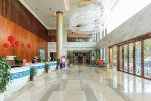 Un hall d’entrée spacieux, doté d’un comptoir de réception, d’un grand lustre et d’un plafond haut.