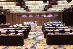 A conference room with rows of tables, chairs, and a stage with a banner. - Wuxi Yuexi Grand Hotel (Huishan Wanda) (Wuxi)