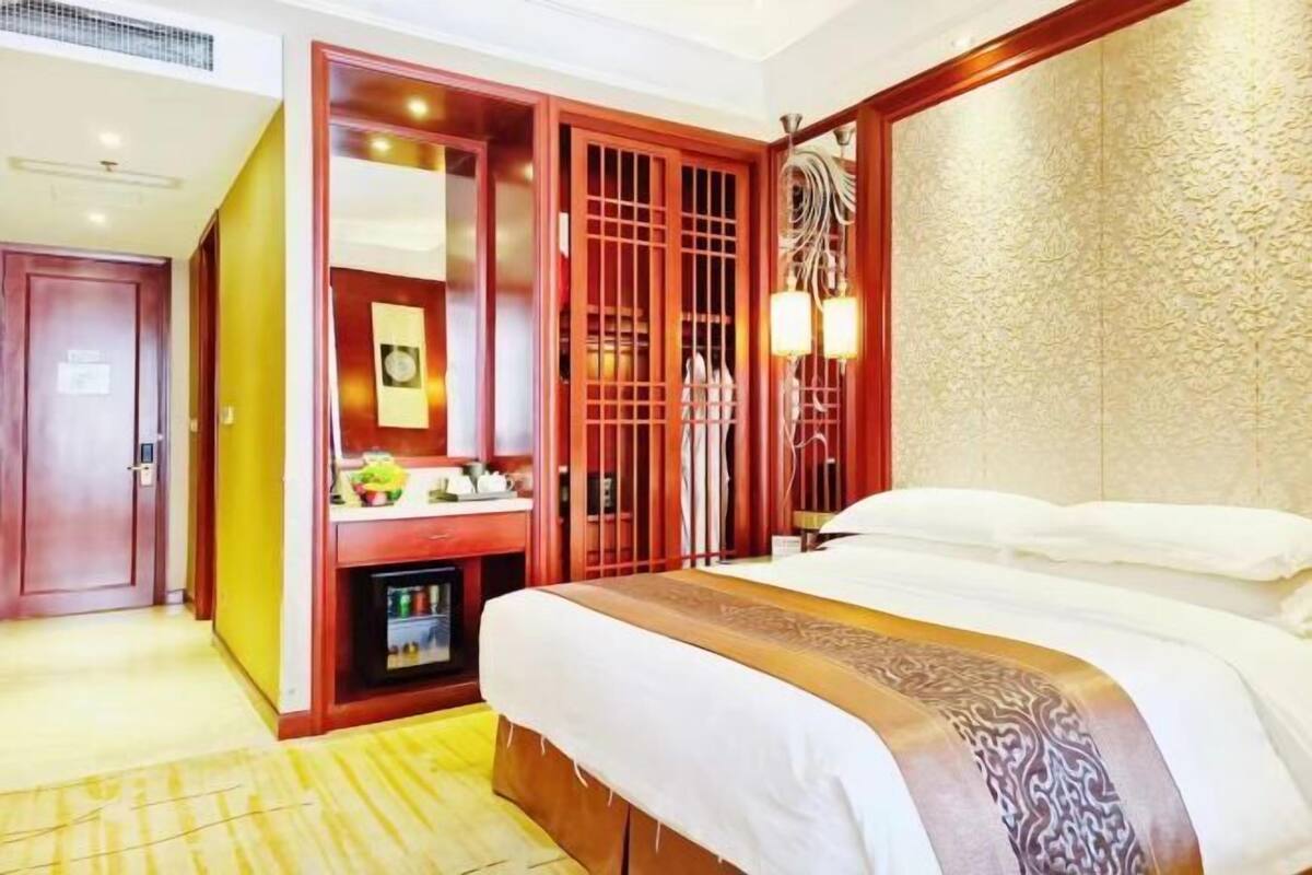 Ein Hotelzimmer mit einem Bett, einem Kleiderschrank, einem Schminktisch und einem Nachttisch.