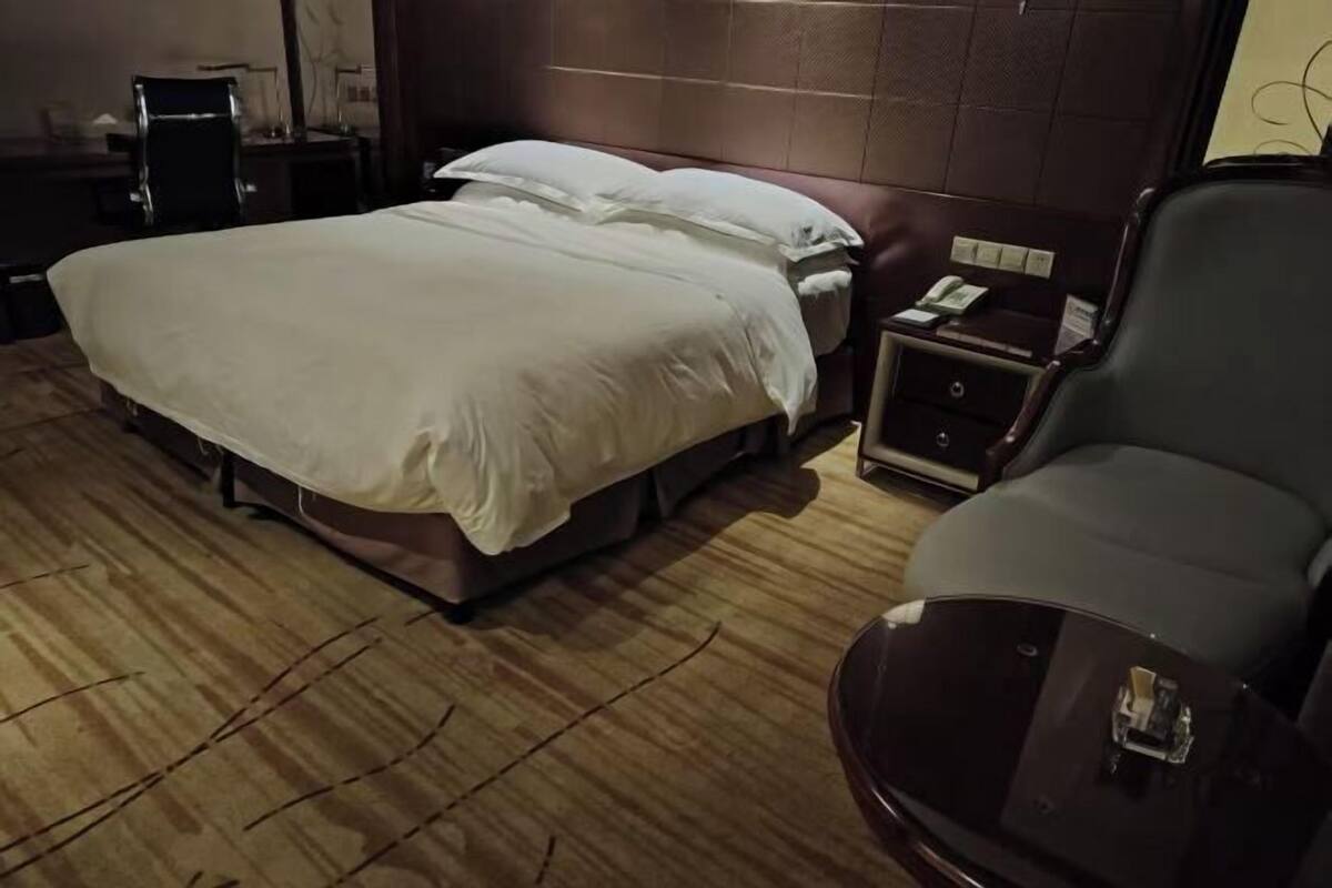 Ein Hotelzimmer mit Bett, Nachttisch, Sessel und Schreibtisch.