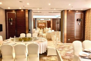 Une salle de conférence avec des tables rondes, des chaises blanches et un tapis à motifs.