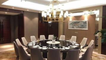 Une table de salle à manger ronde, entourée de chaises, un lustre et un tableau accroché au mur.