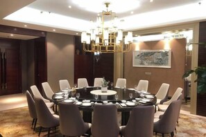 Mesa redonda de jantar com cadeiras, um lustre e um quadro na parede.