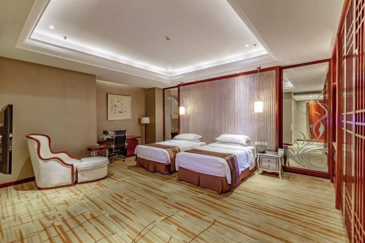 Ein Hotelzimmer mit zwei Betten, einer Couch, einem Schreibtisch und einem Spiegel.