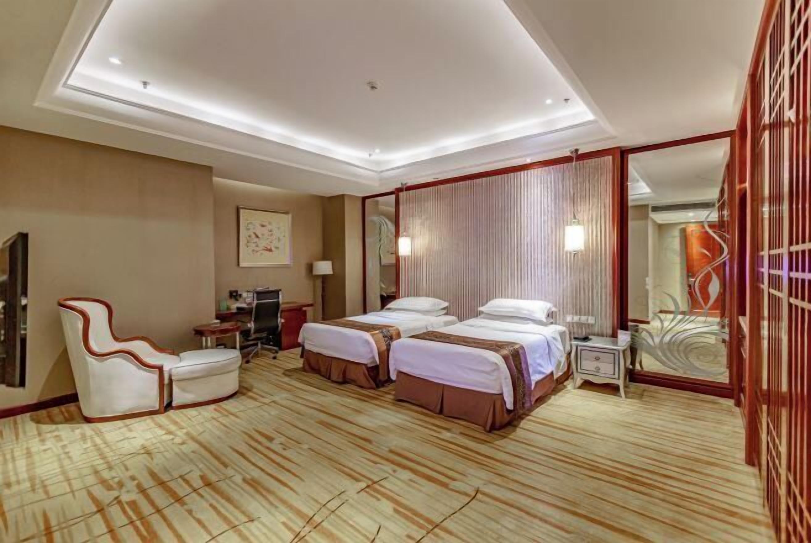 Habitación de hotel con dos camas, un sofá, un escritorio y un espejo.