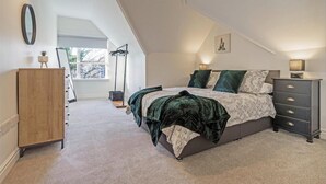 Quarto com cama, penteadeira, espelho, abajur e janela.