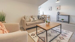 Sala de estar com sofá, mesa de centro e aparador com plantas.