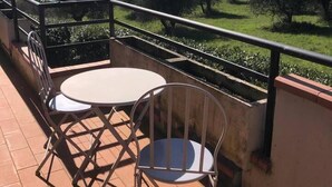 Une terrasse avec deux tables rondes et des chaises, donnant sur un paysage composé d’arbres et de collines lointaines.