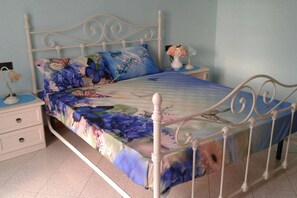 A bedroom with a floral bedspread, a white metal bed frame, a nightstand with a lamp, and a vase with flowers on the nightstand. - Casa Annick Holiday Home Chianti Area Florence (Barberino Tavarnelle)