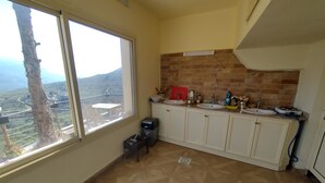 A kitchen with two sinks, a brick backsplash, and a view of a mountainous landscape through large windows. - Maison de la Vallee Private Guest House Great View (Kahlouniyeh)